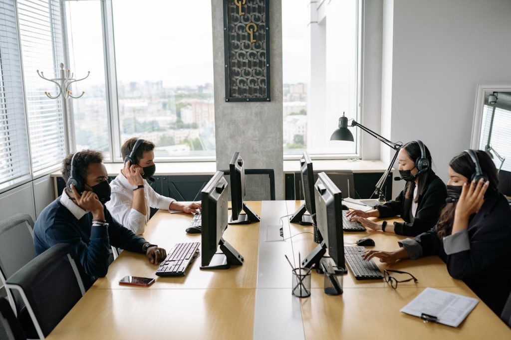 group-of-men-and-women-working-in-the-office-8866725 Professional team in a modern call center working collaboratively with headsets and computers.