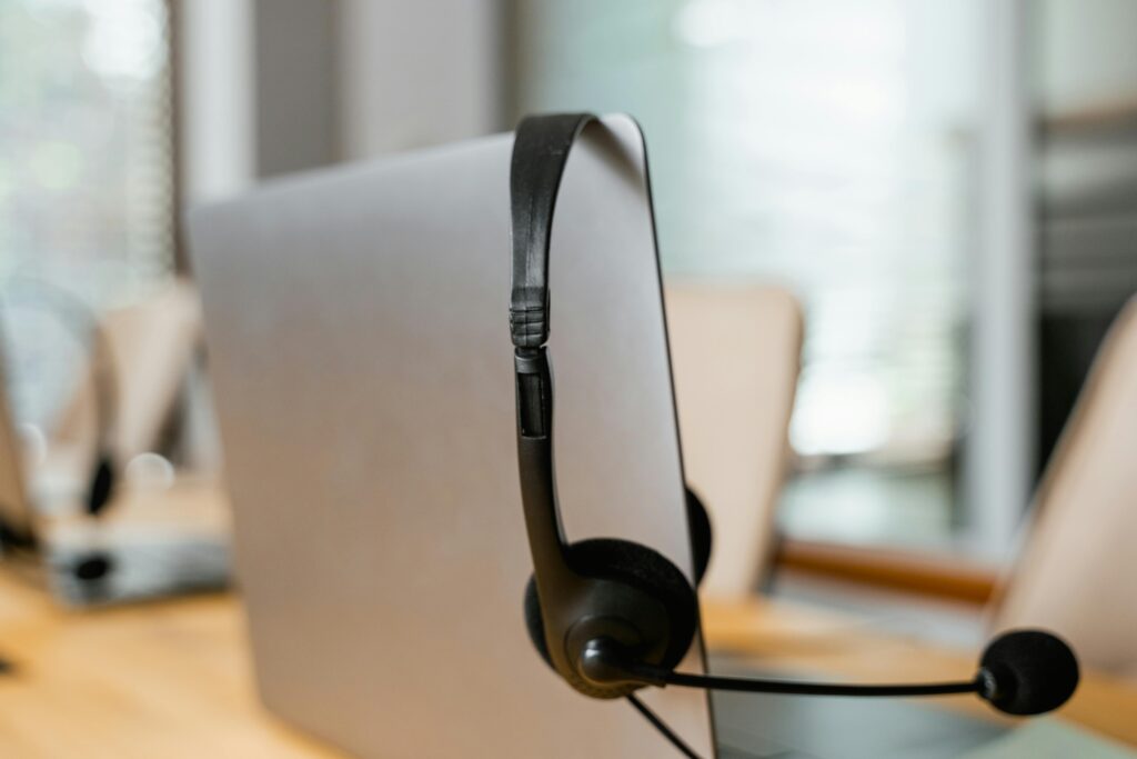 pexels photo 7709216 7709216 A headset hanging on a computer in a modern office setting for customer support.